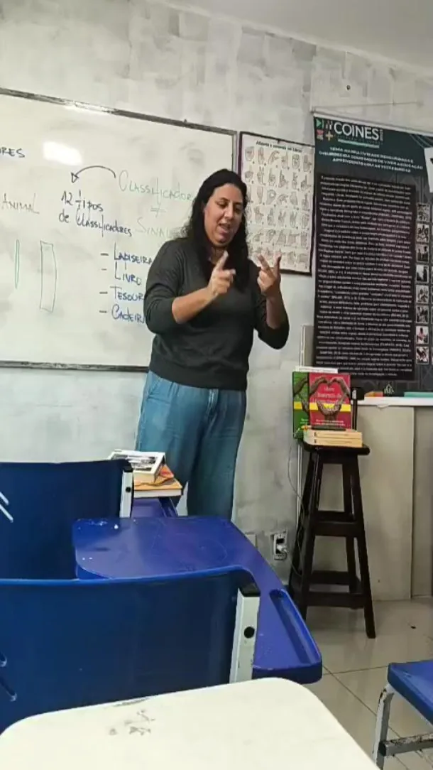 Professora do Integrando ensinando classificadores em Libras diante do quadro, em aula do curso