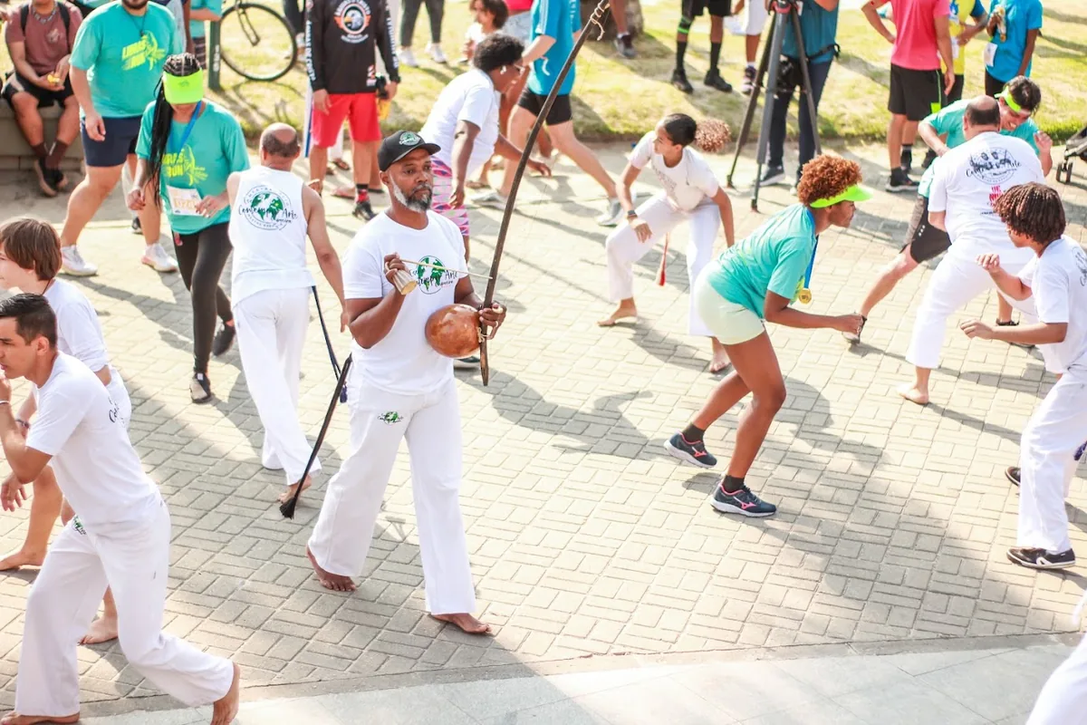 Roda de capoeira no Parque Madureira, com pessoas de branco jogando e uma plateia ao redor
